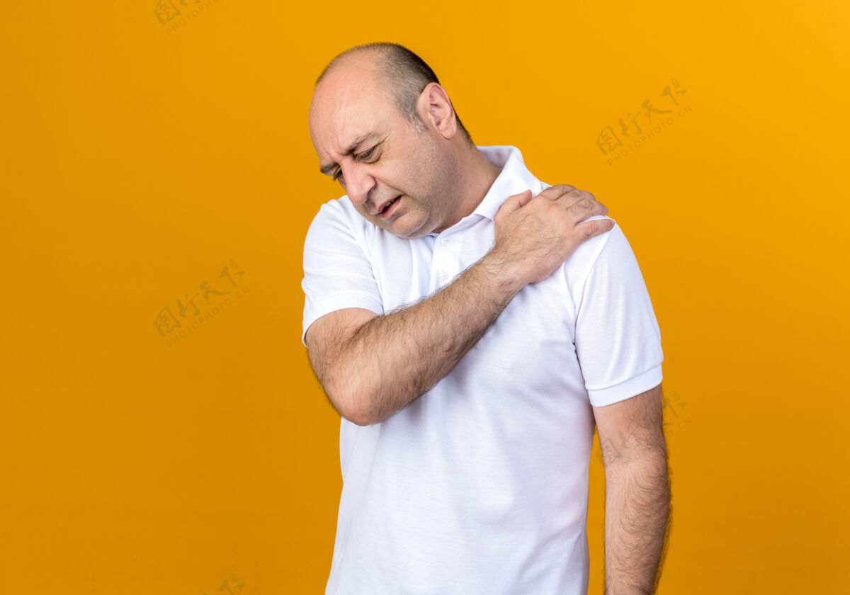 背景受伤的休闲成熟男子抓住肩膀隔离在黄色背上与复制空间受伤随意成熟