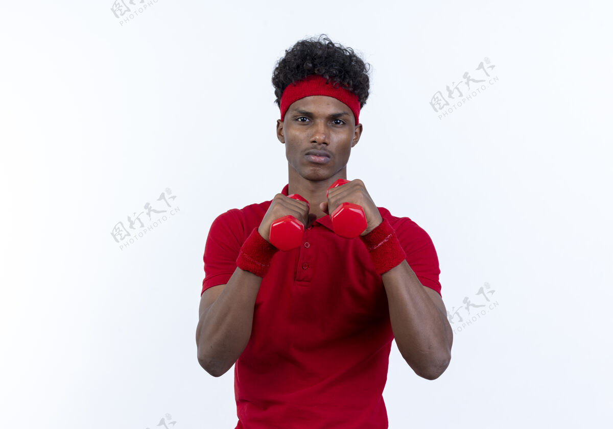 非裔美国人自信的年轻美国黑人运动男子戴着头带和腕带站在战斗的姿势 举着白色背景上孤立的哑铃抱着哑铃自信