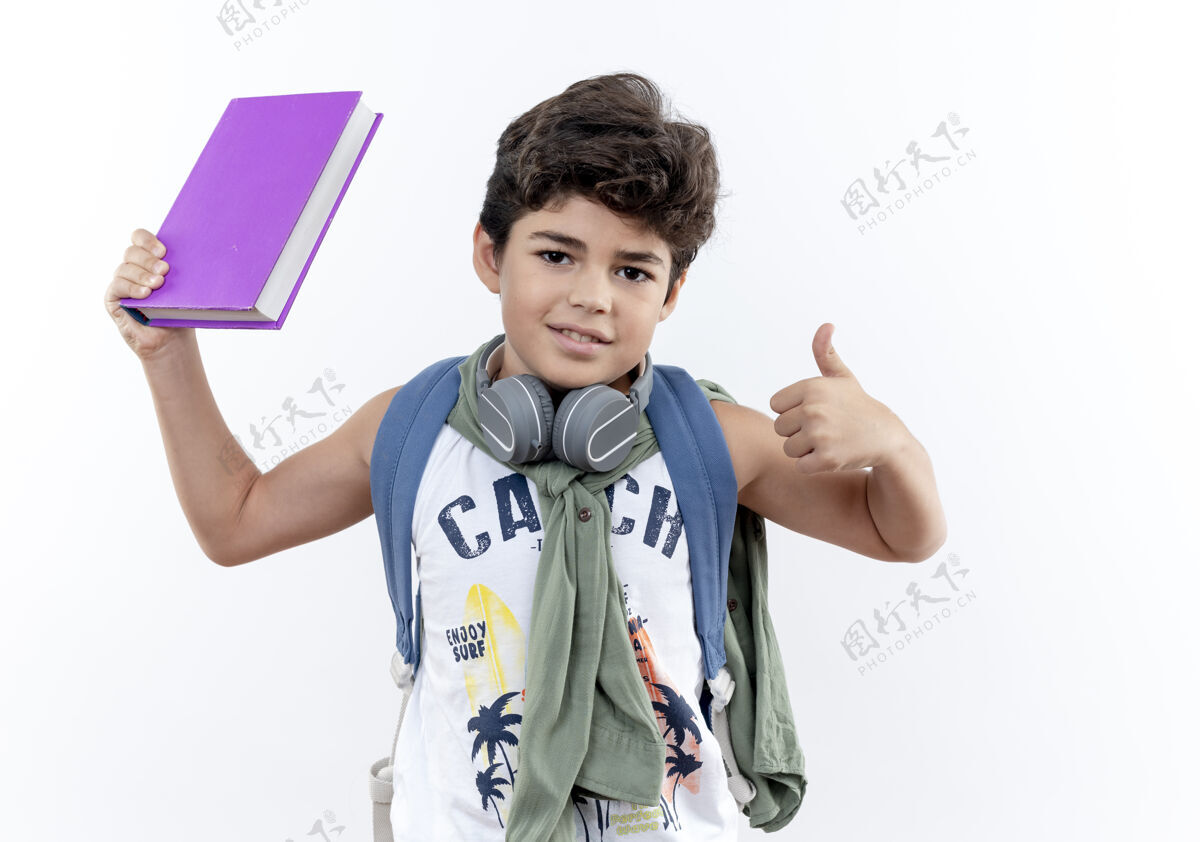包戴着书包和耳机的小男孩高兴地举起了大拇指 孤立地站在白色的背景上戴上背小学生