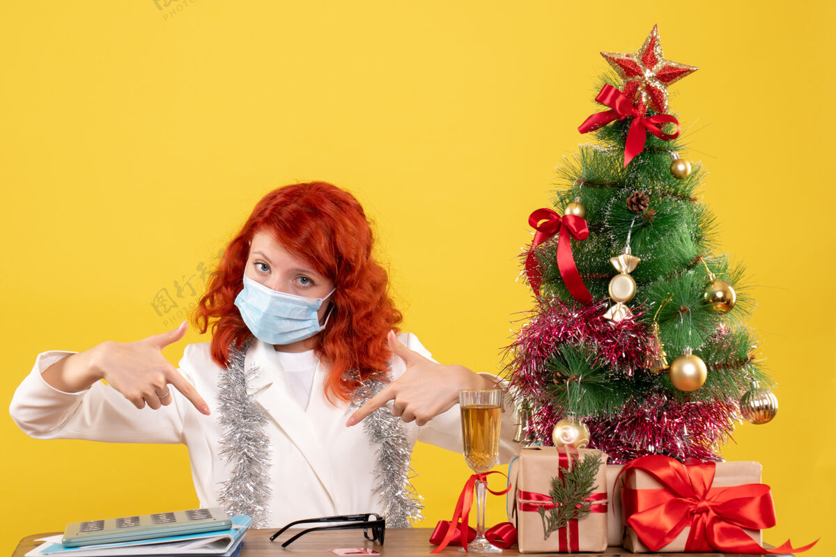人前视图女医生围绕圣诞树和礼物坐在面具礼物漂亮年份
