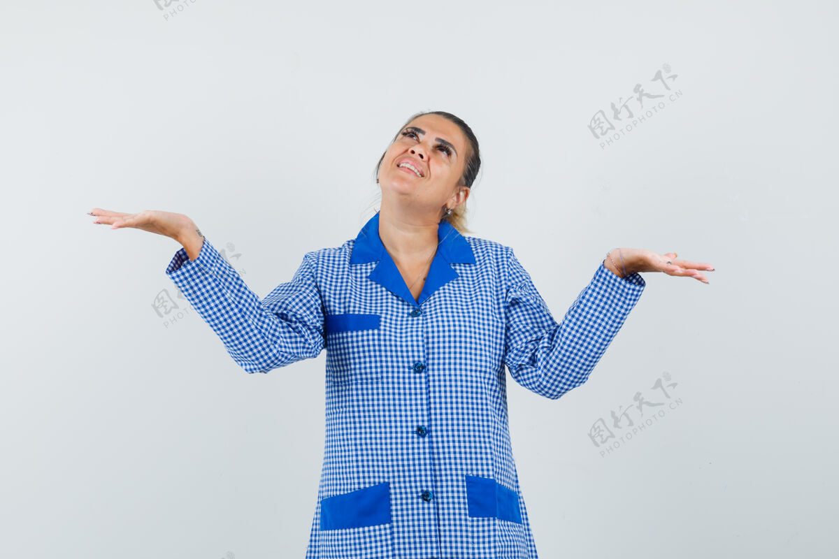 护理年轻女子摊开手掌 拿着一件蓝色方格睡衣衬衫的大东西 看起来很开心正视图时尚蔓延人