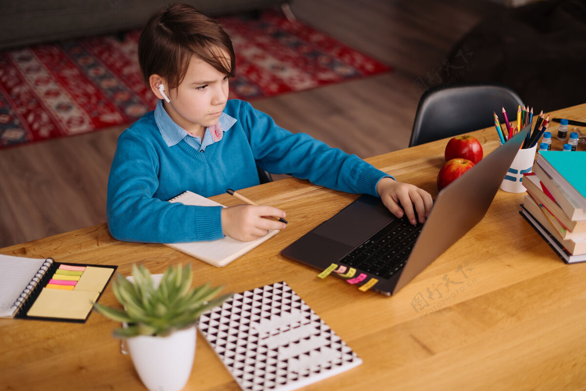 技术一个未成年男孩用笔记本电脑和他的老师打视频电话 在线上课 做笔记房子通话洋葱