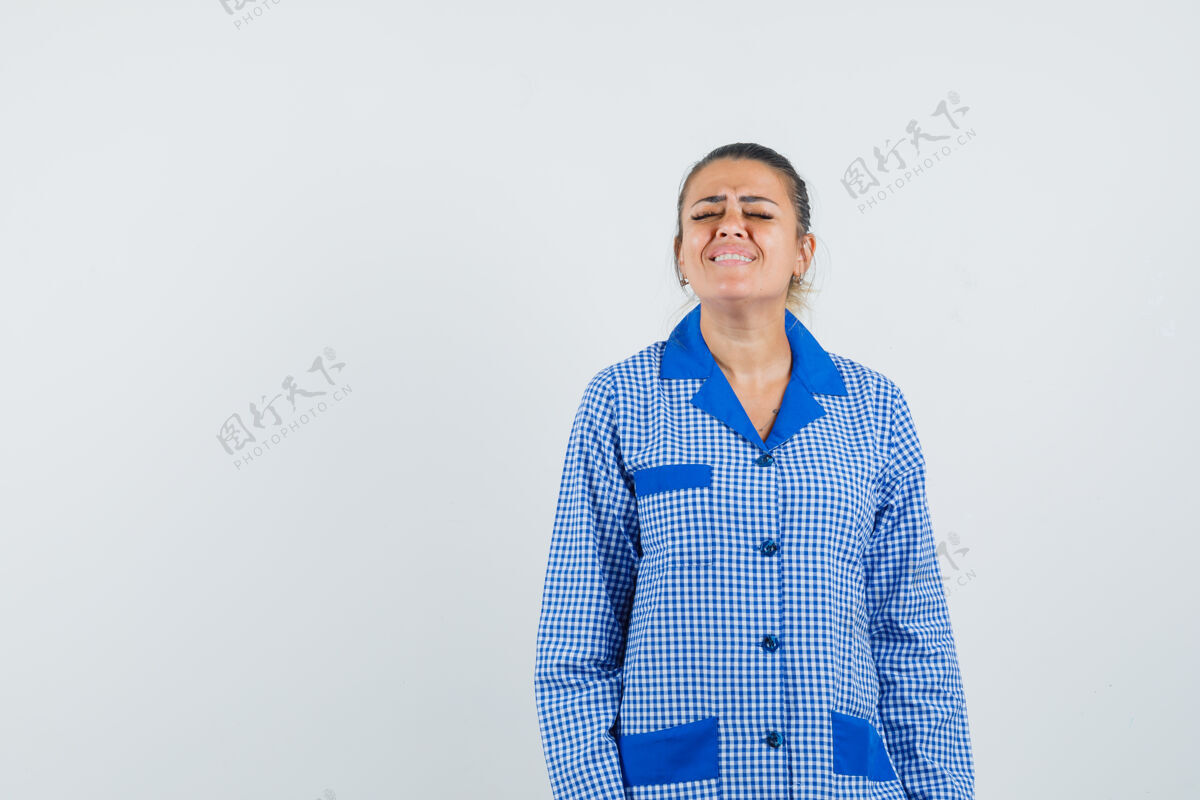 成人穿着蓝色格子睡衣衬衫的年轻女子站直了 摆着姿势 看上去很烦躁 正对着前方方格布直女孩