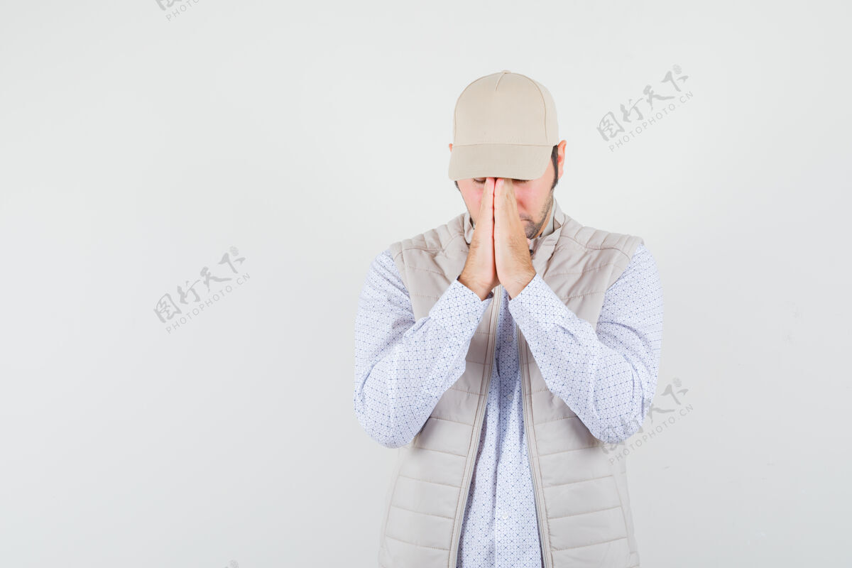 男人年轻人穿着米色夹克 戴着帽子 站在祈祷的姿势 专注地看着前方成年人人帽子