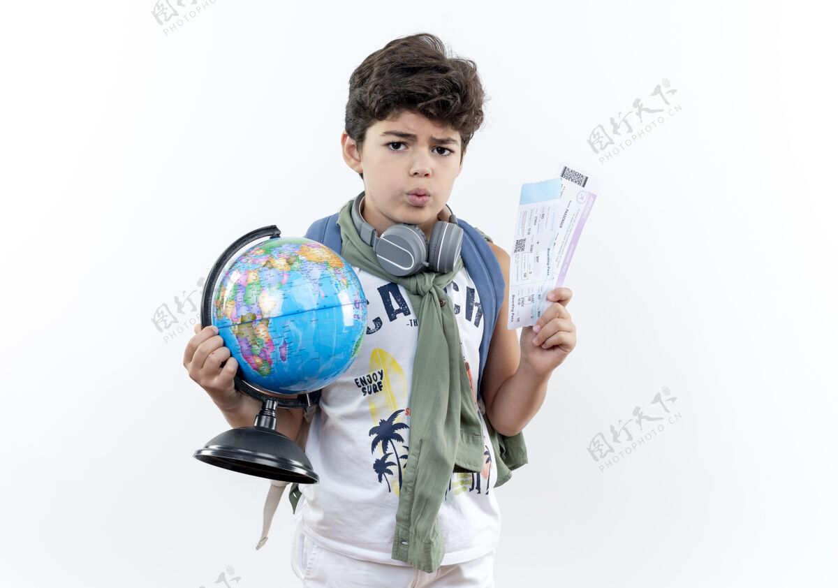 抱那个戴着背包和耳机 拿着地球仪和隔离在白色背景上的票的关心的小男孩地球仪耳机背