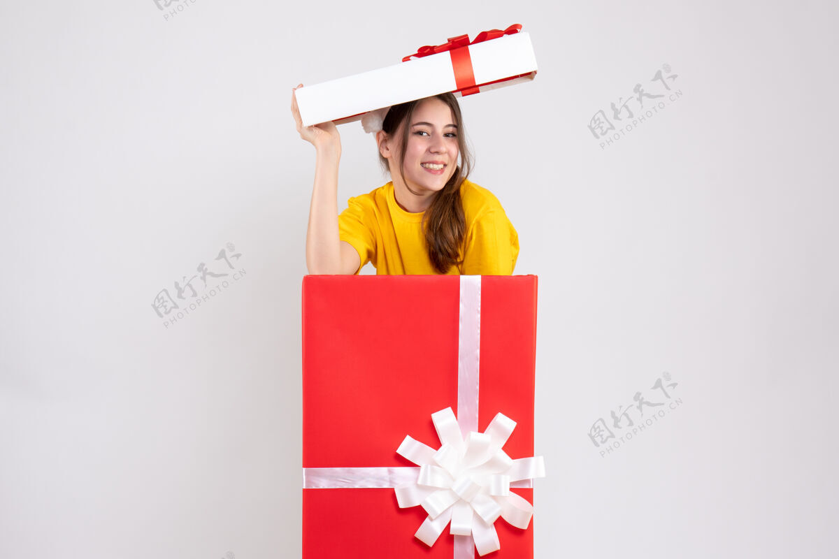 幸福的女孩正面图：戴着圣诞帽的幸福女孩站在大礼盒里礼品盒立场大
