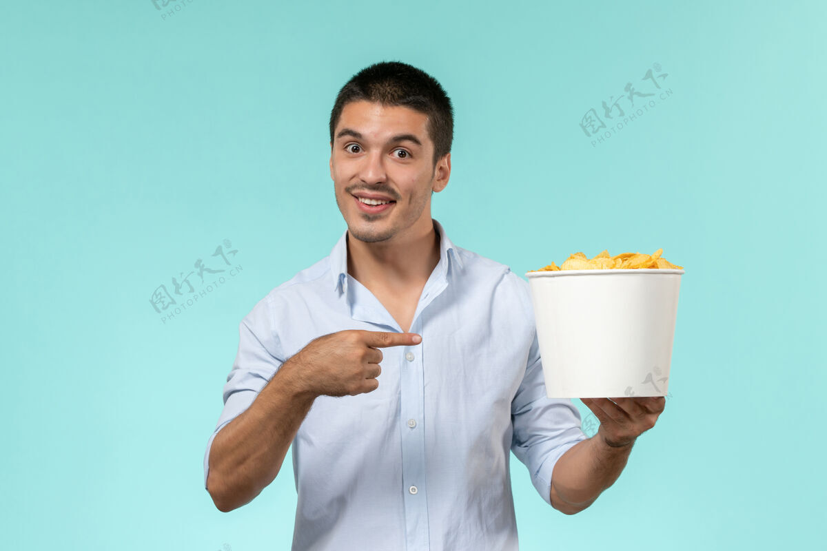 男人前视图年轻人拿着篮子和土豆cips在蓝色的墙上遥远的电影电影院孤独的男人年轻人视图肖像