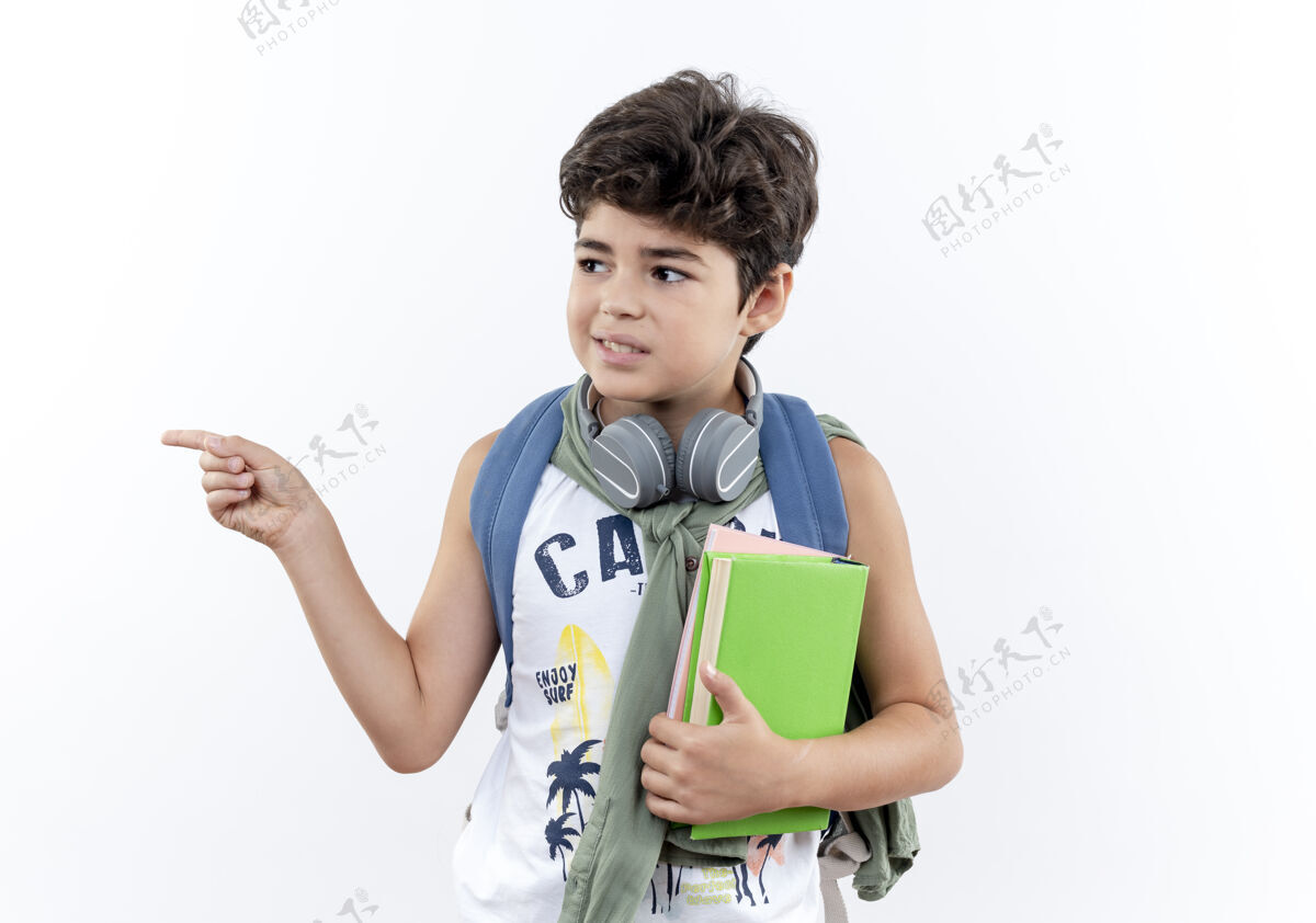 小学生看着身边高兴的小男生背着书包 戴着耳机拿着书 指着旁边隔离的白色背景和复印空间点请穿小的