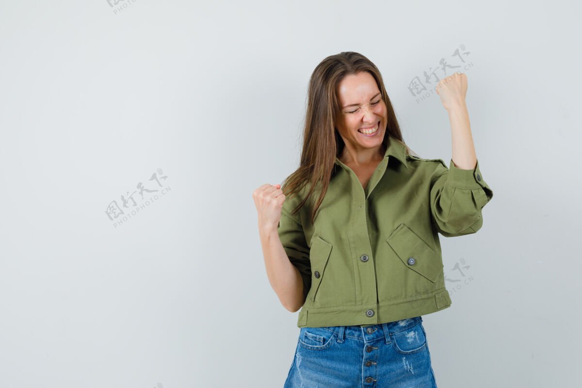 时尚身着绿色夹克短裤的年轻女士展示着赢家的姿态 看上去很幸福短裤女士赢家