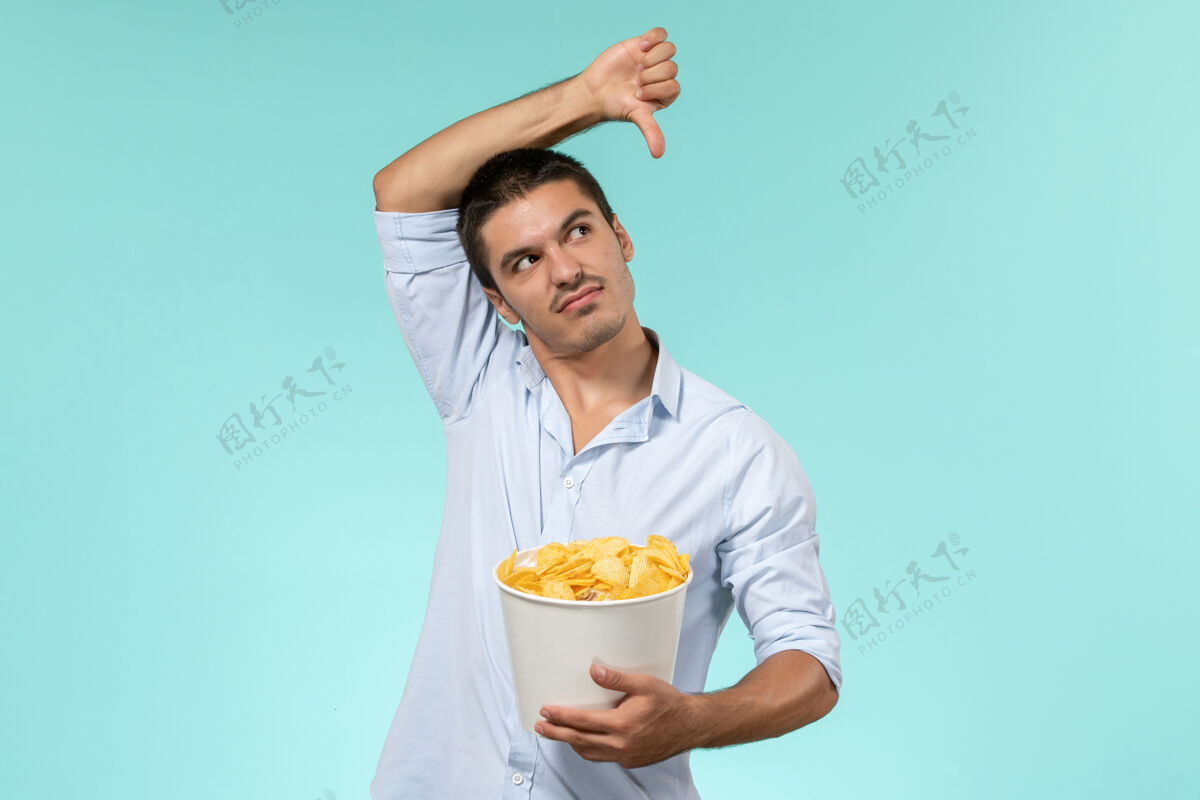 成人正面图年轻人拿着篮子和土豆在蓝色的墙上cips远程电影电影院孤独的男人土豆肖像电影