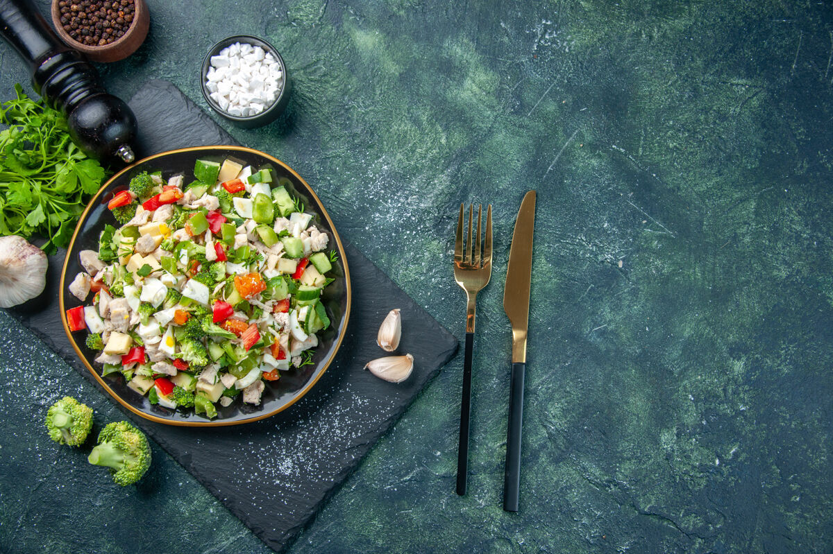 晚餐顶视图美味的蔬菜沙拉在深蓝色背景色的盘子里烹饪午餐餐厅食物减肥餐勺子盘子午餐