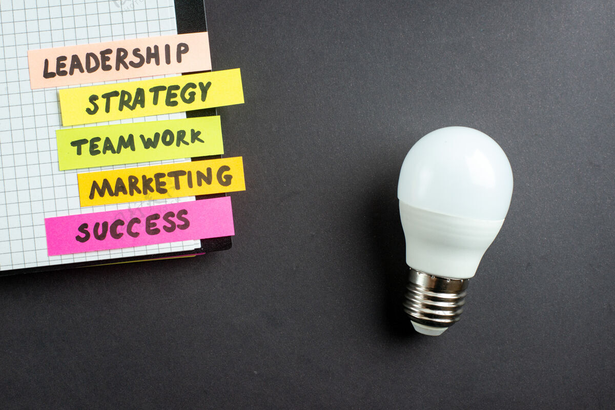 灯顶视图激励商业笔记带记事本在黑暗背景下商业工作成功工作策略团队合作营销办公室领导灯泡工作战略