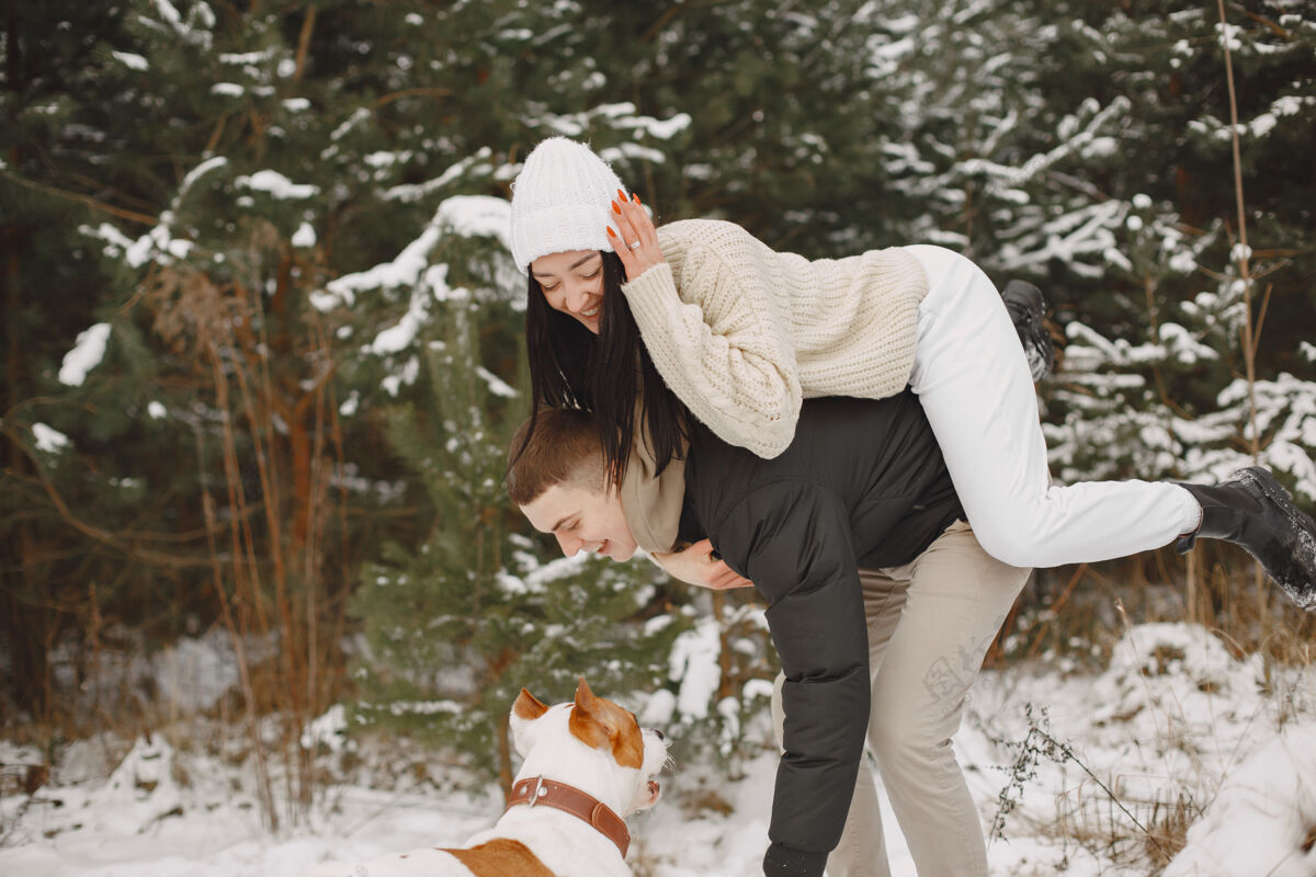 外面生活方式拍摄的夫妇在雪林与狗舒适约会快乐