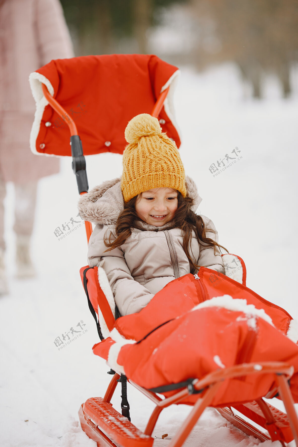 公园雪地公园里坐着雪橇的小女孩温暖毛衣户外