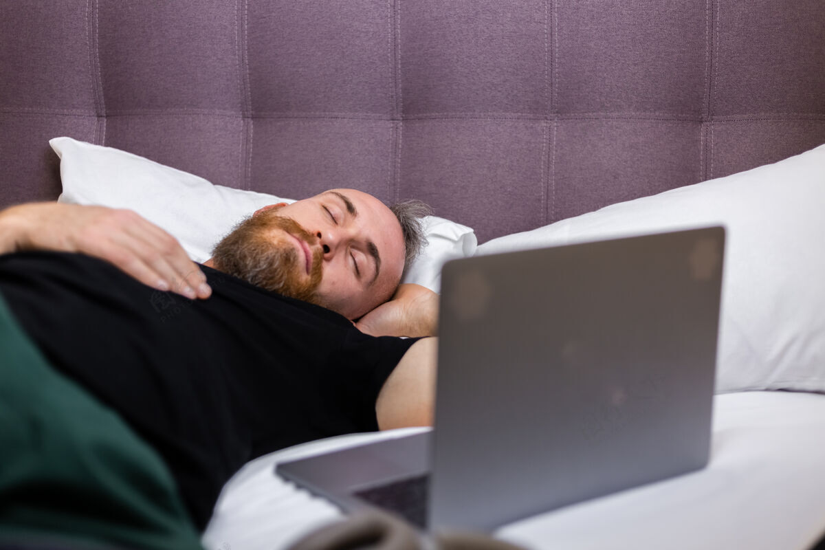 技术高加索男人在家躺在床上看笔记本电脑在线房子室内
