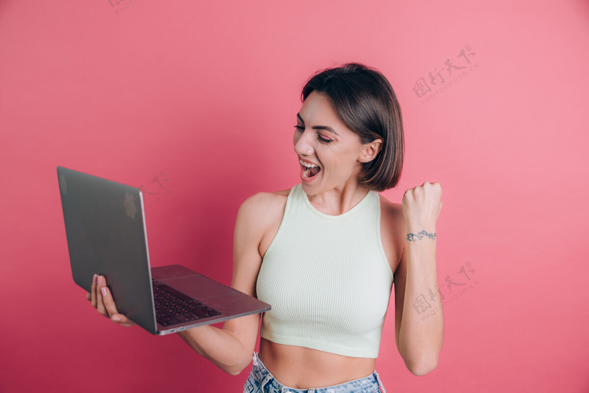 胜利粉色背景的女人拿着笔记本电脑工作成人个人电脑