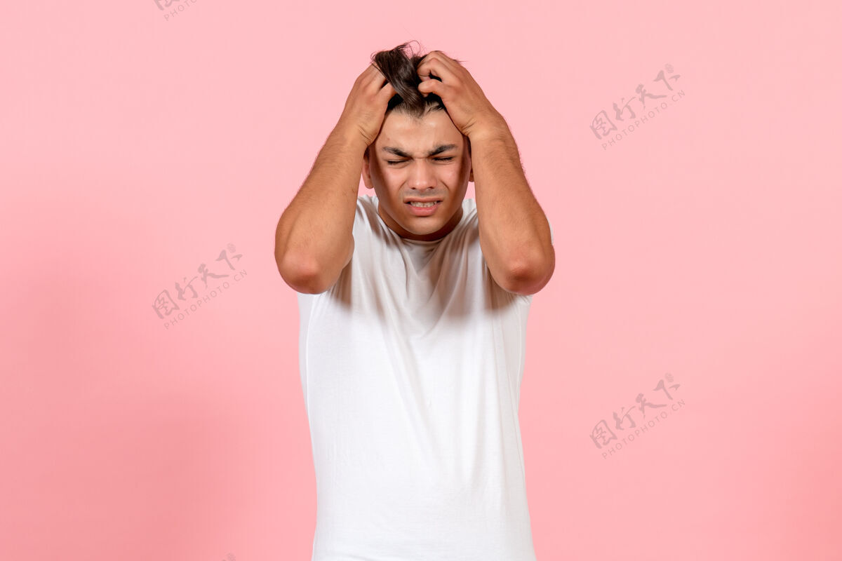 年轻男性正面图粉色背景上头痛的年轻男性男性彩色模特感慨人脸情绪