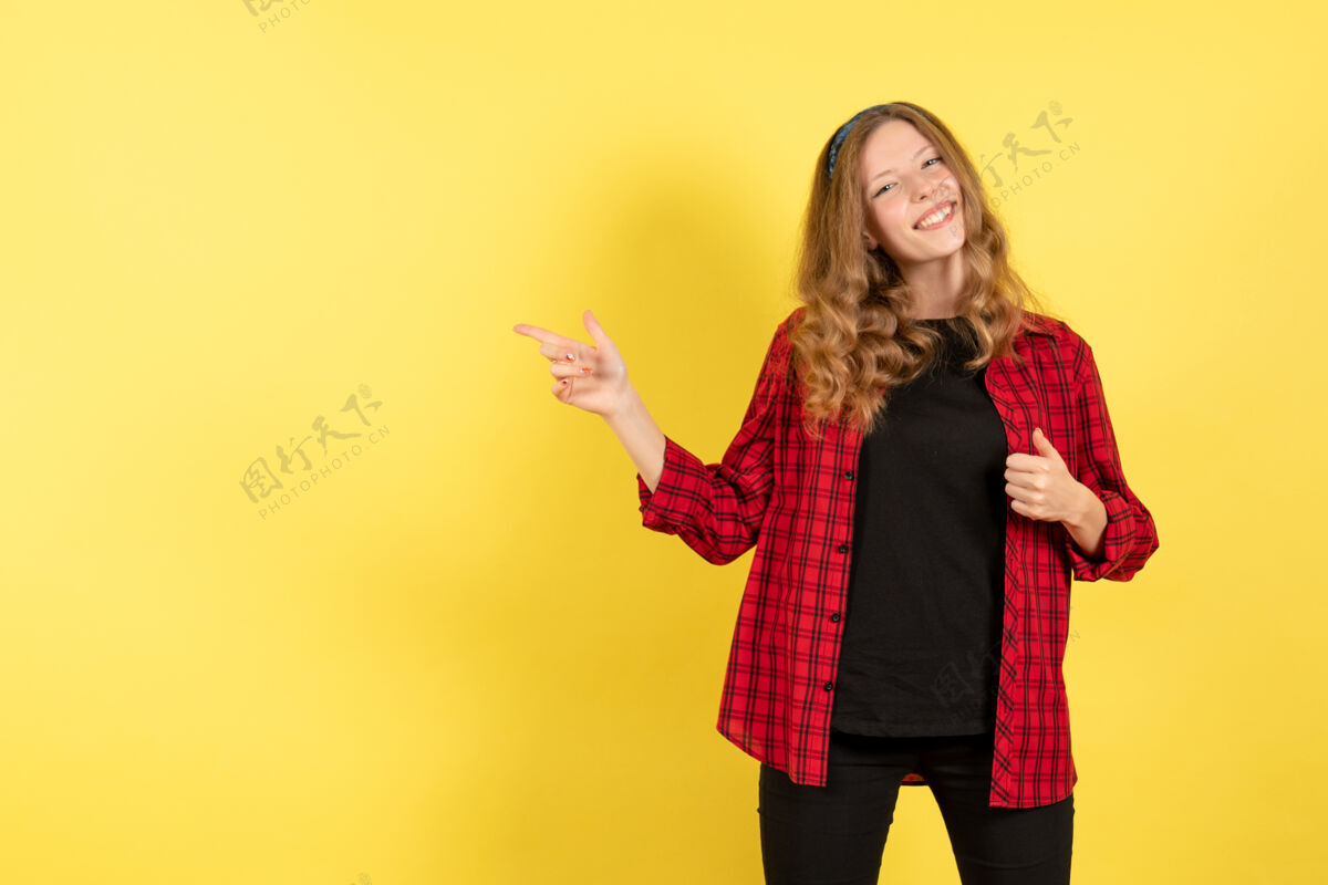 情感正面图身着红色格子衬衫的年轻女性在黄色背景上微笑人类女孩情感色彩模特儿人年轻女性成人