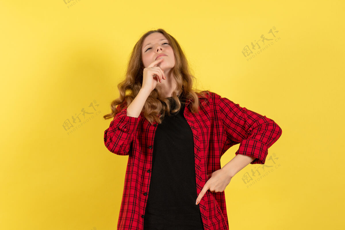 思考正面图身着红色格子衬衫的年轻女性站在黄色背景上思考模特女孩人类女性的色彩情感漂亮站格子