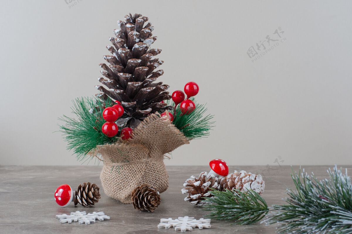 圆锥体用冬青浆果和树枝装饰的松果放在大理石桌上圣诞节冬天松树