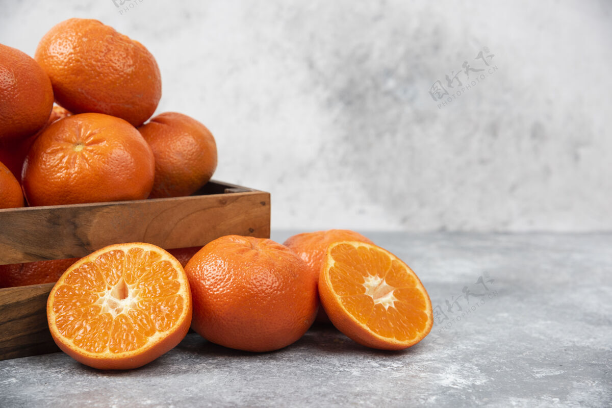 热带石桌上放着一个木制的旧盒子 里面装满了多汁的橙子成熟异国情调水果