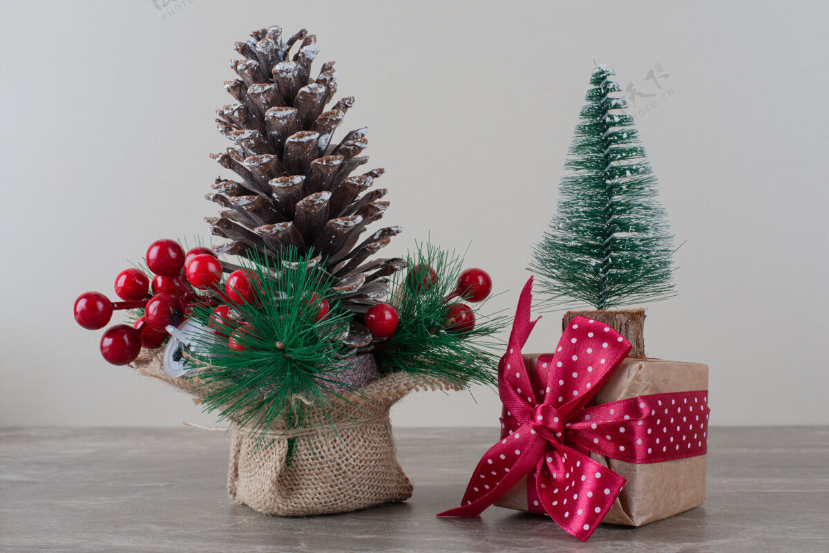 冬天松果装饰冬青浆果和礼品袋在大理石桌上圆锥体节日圣诞节