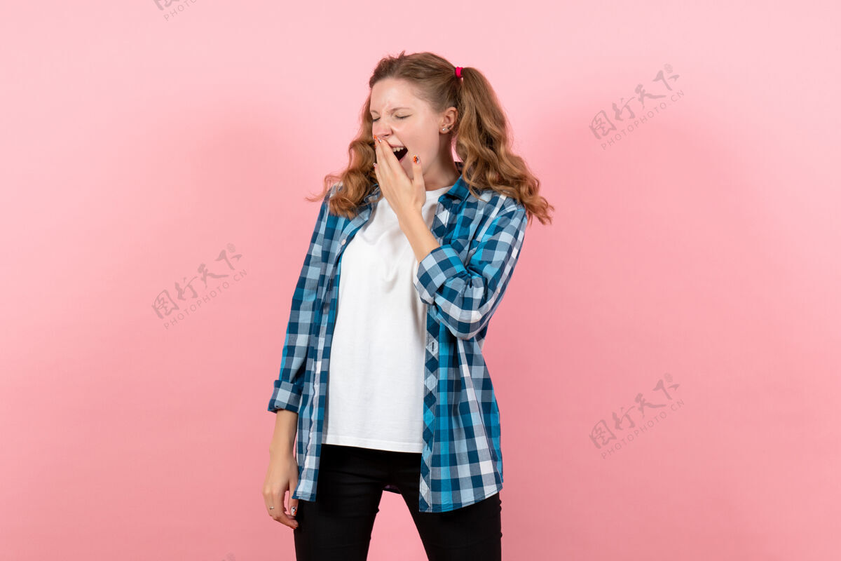 格子正面图身着蓝色格子衬衫的年轻女性在粉色背景上打呵欠情感女孩时尚模特青年小子成人人电话