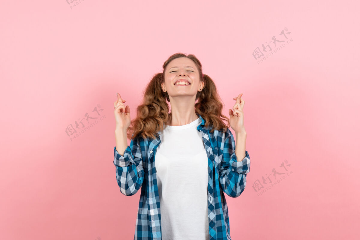 人正面图：穿着格子衬衫的年轻女性在粉色背景上摆姿势 手指交叉 女性青春色彩 儿童模特年轻格子微笑