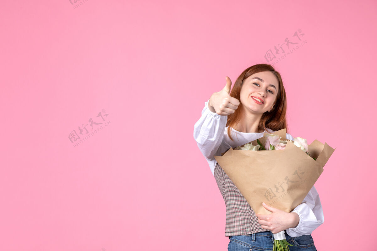 人正面图：带花朵的年轻女性作为女性节礼物 粉色背景 横向女性化三月女性约会玫瑰爱情性感花玫瑰花束