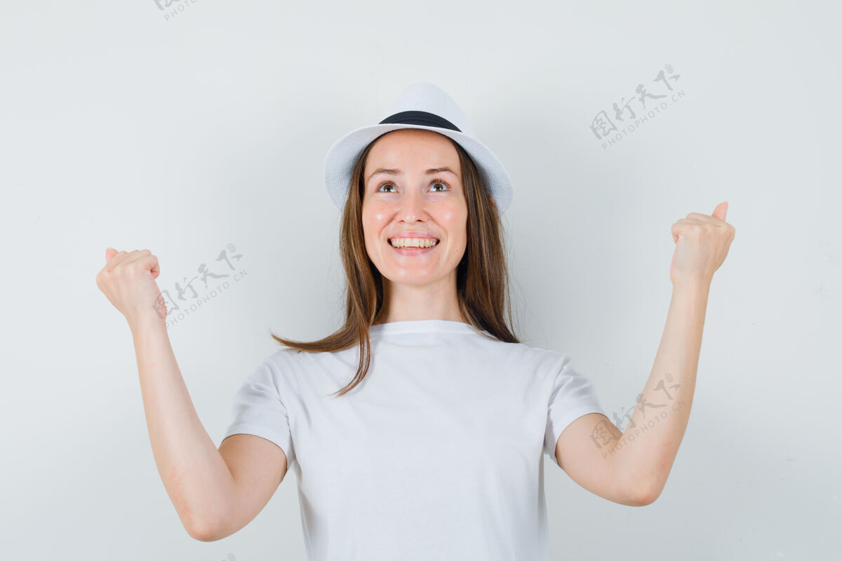 帽子穿着白色t恤帽子展示赢家姿态的年轻女孩 看起来很幸福漂亮快乐展示