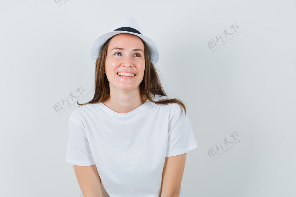 女士年轻的女士戴着白色的t恤帽子抬头望去 看上去很高兴性感人性化连衣裙