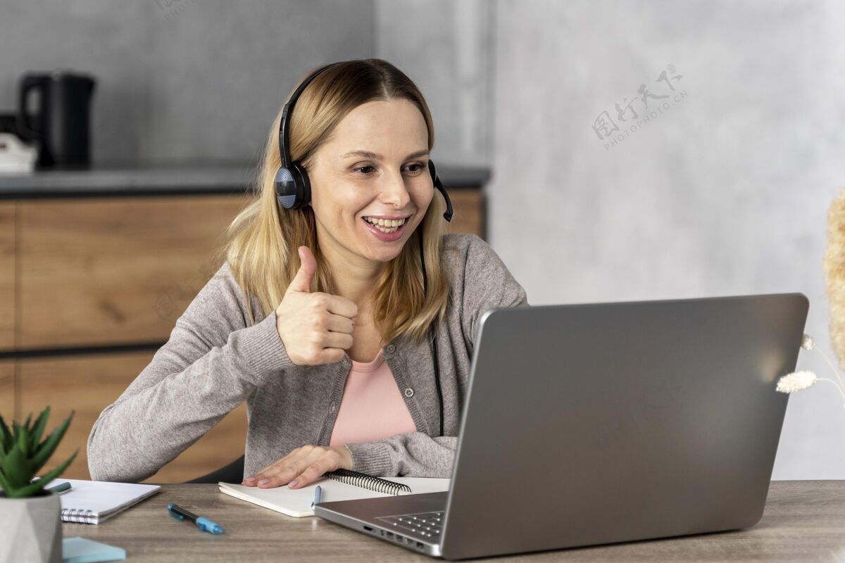 笔记本电脑戴着耳机在笔记本电脑上工作的女人设备笔学习