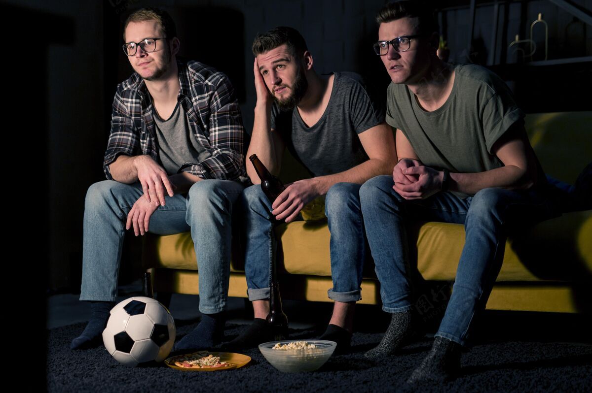 男人三位男性朋友一边吃零食和啤酒 一边看电视上的体育节目看伙伴最好的伙伴