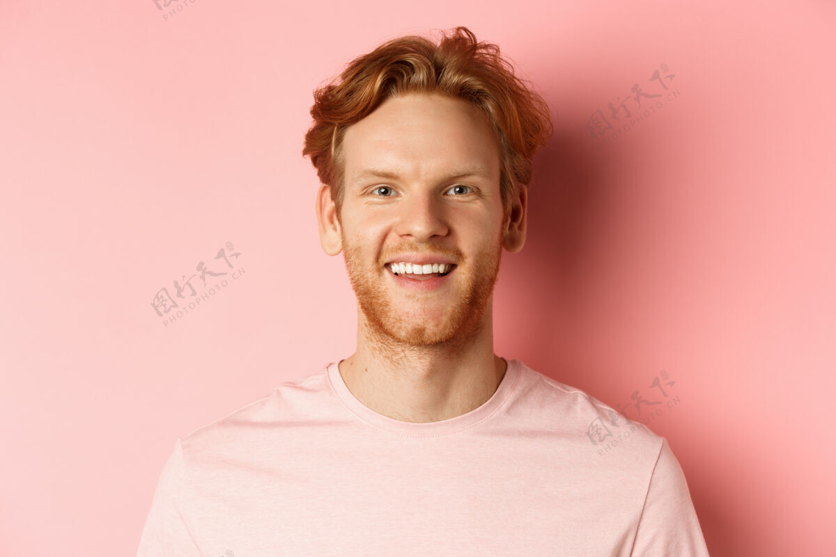 休闲一个快乐的红头发男人的头像 留着胡子 牙齿洁白 对着镜头兴奋地微笑 站在粉色的背景上姜黄色人胡须