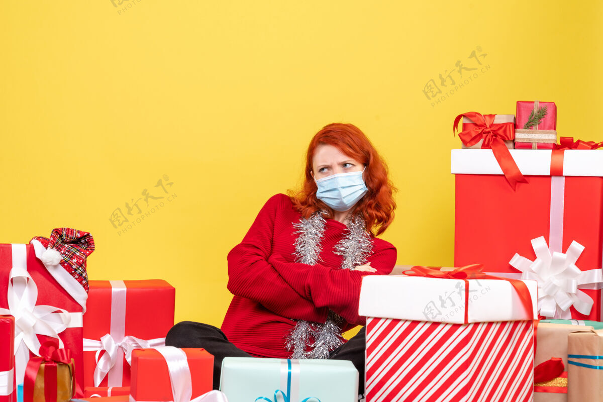 礼物前视图年轻女子围坐在圣诞礼物与面具上的黄色新年情感冠状病毒年轻女子周围病毒