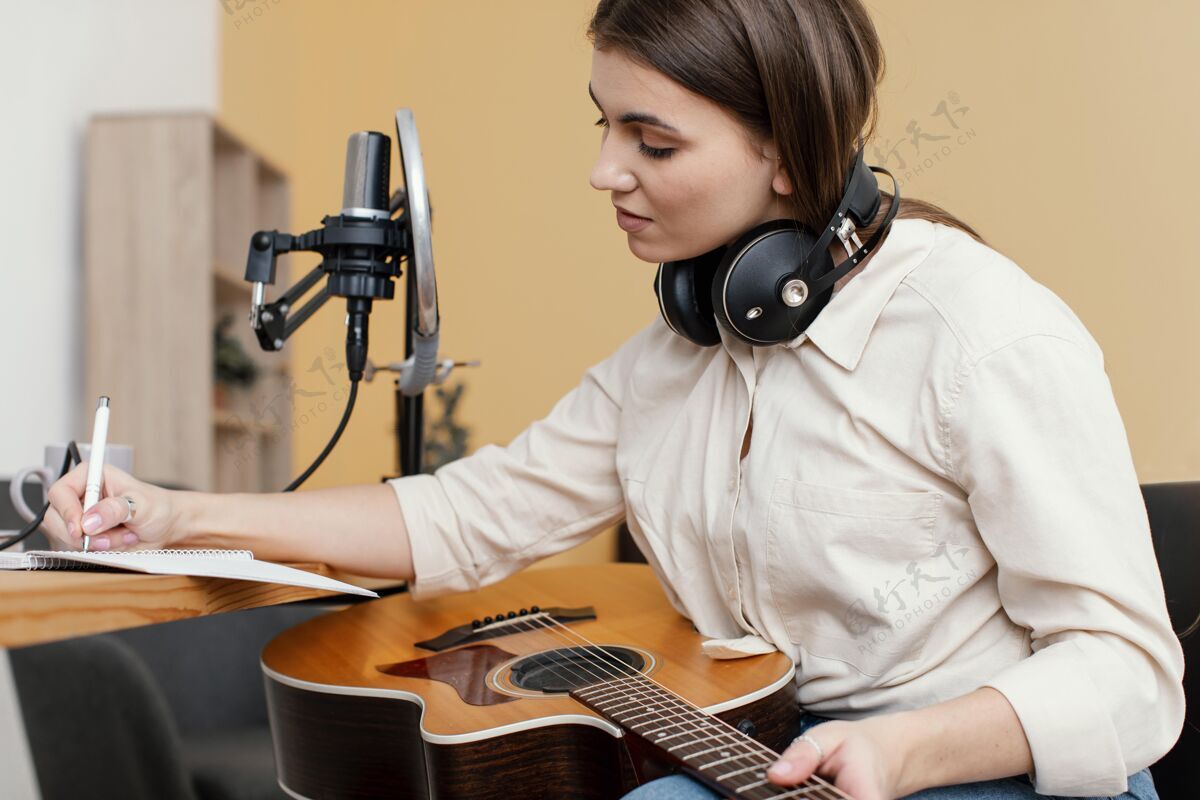 表演女音乐家在家边弹原声吉他边写歌的侧视图音乐家原声吉他房子