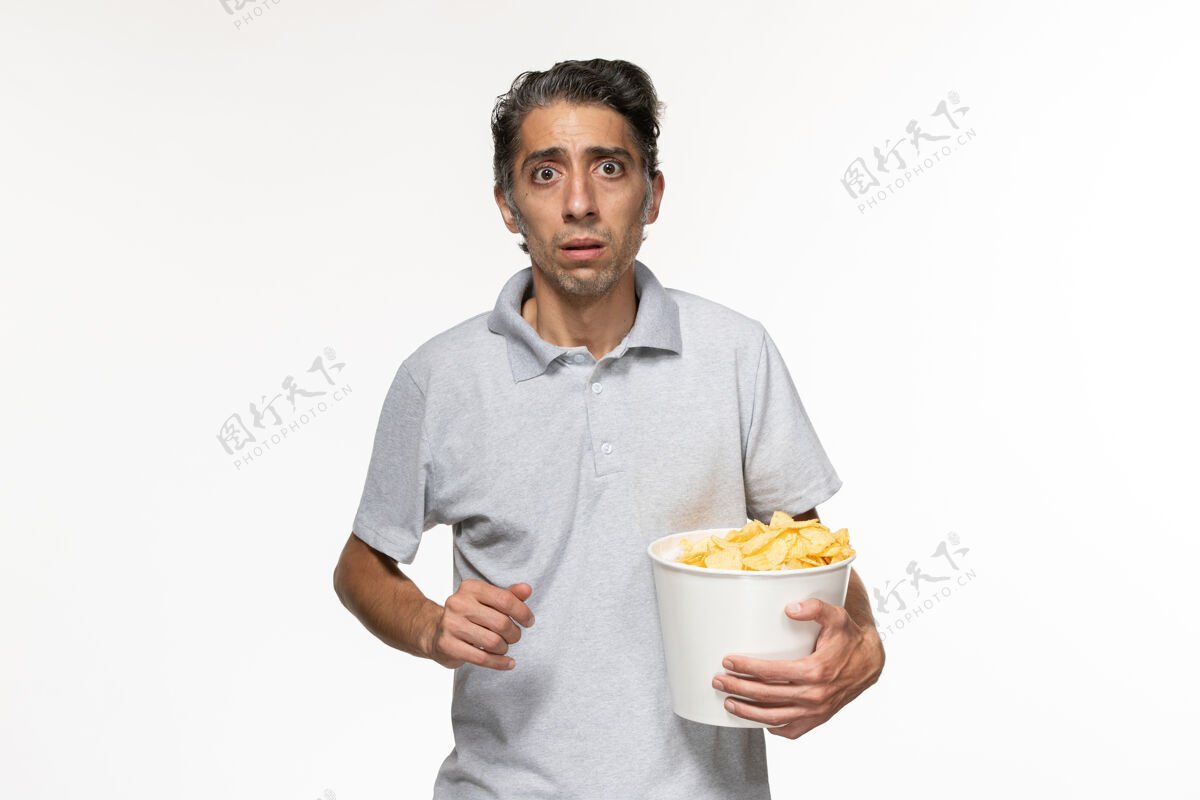服务员正面图年轻男性在吃薯片看电影在白色的表面电影前面电影院
