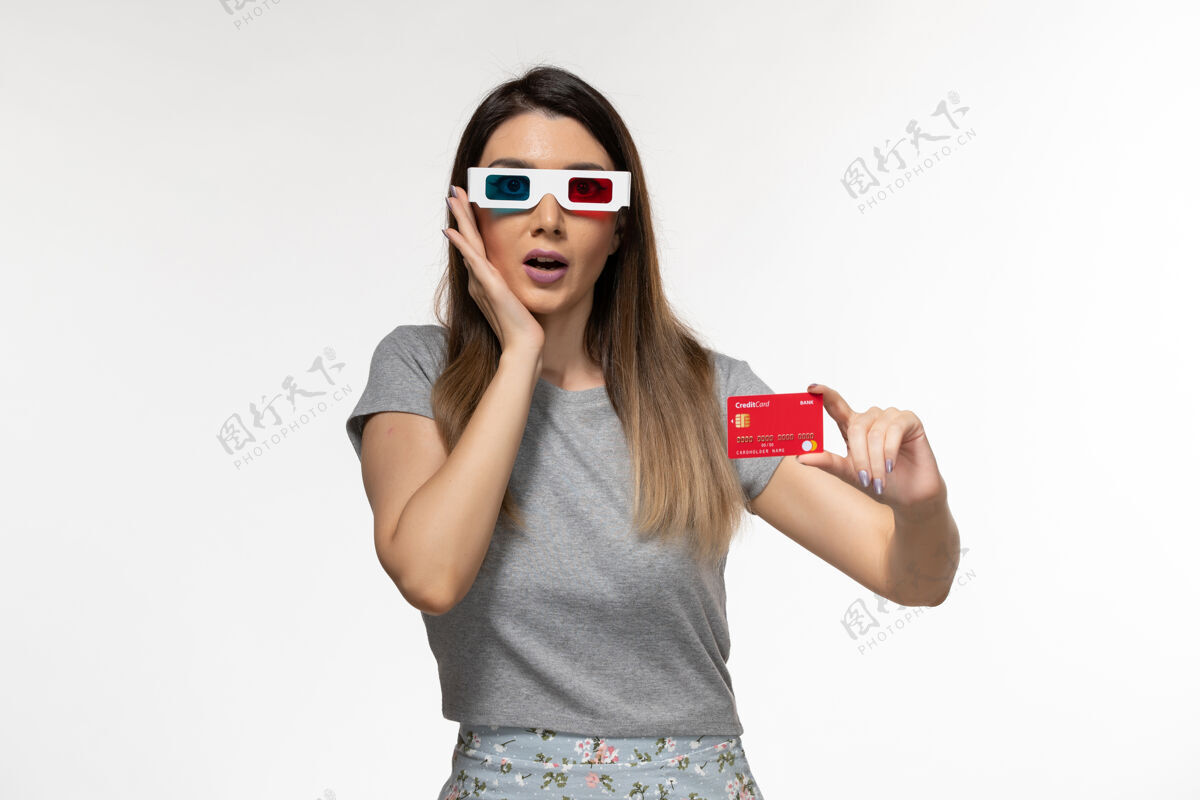 前面正面图：年轻女性戴着d墨镜手持红色银行卡 坐在浅白的办公桌上漂亮遥远电影院