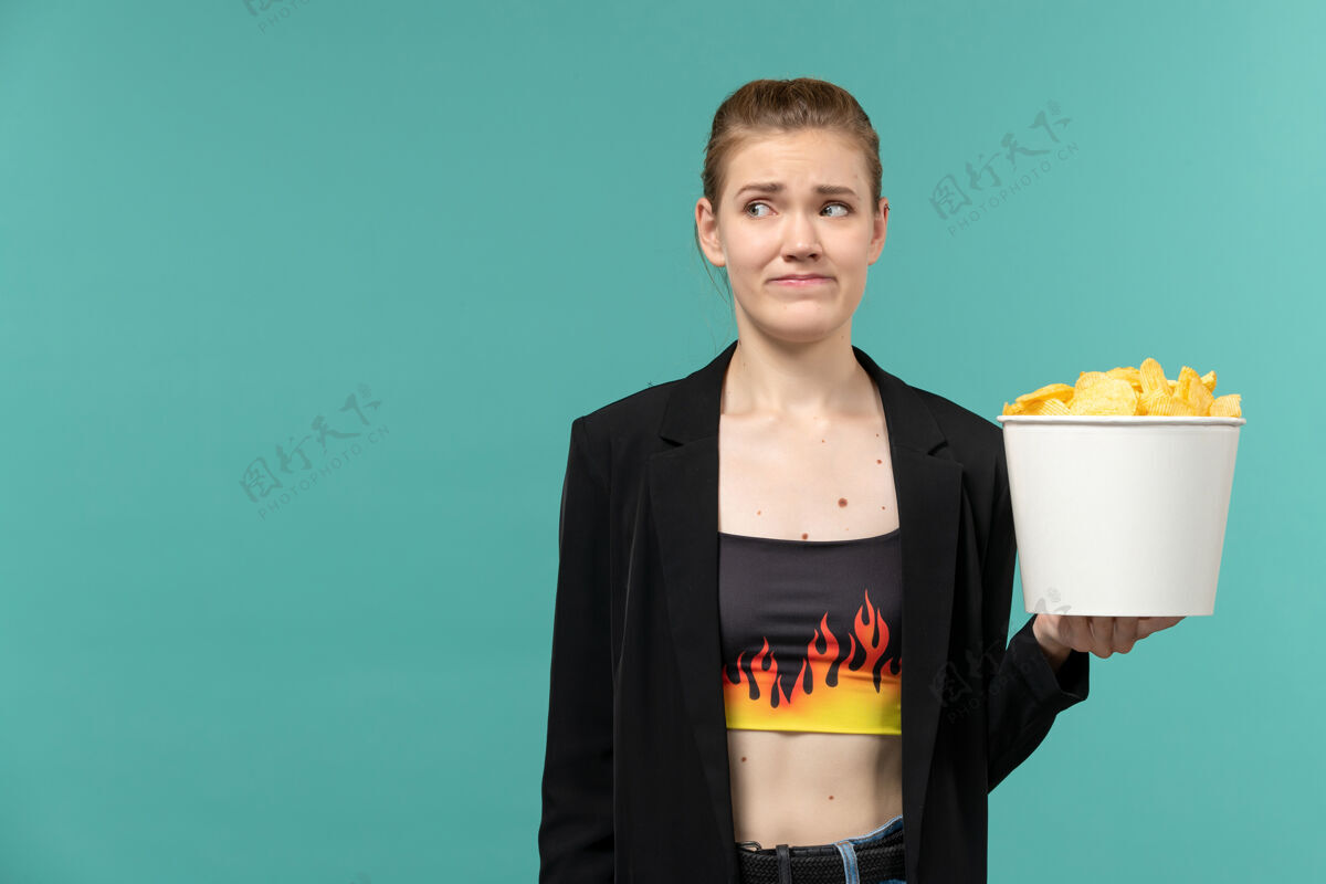前面正面图：年轻的女性拿着薯片在蓝色的水面上看电影服务员电影西装