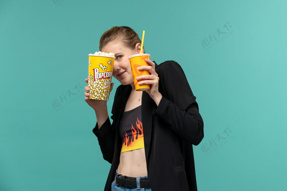 剧院正面图年轻女性拿着爆米花拿着饮料 在蓝色的桌子上看电影爆米花电影看