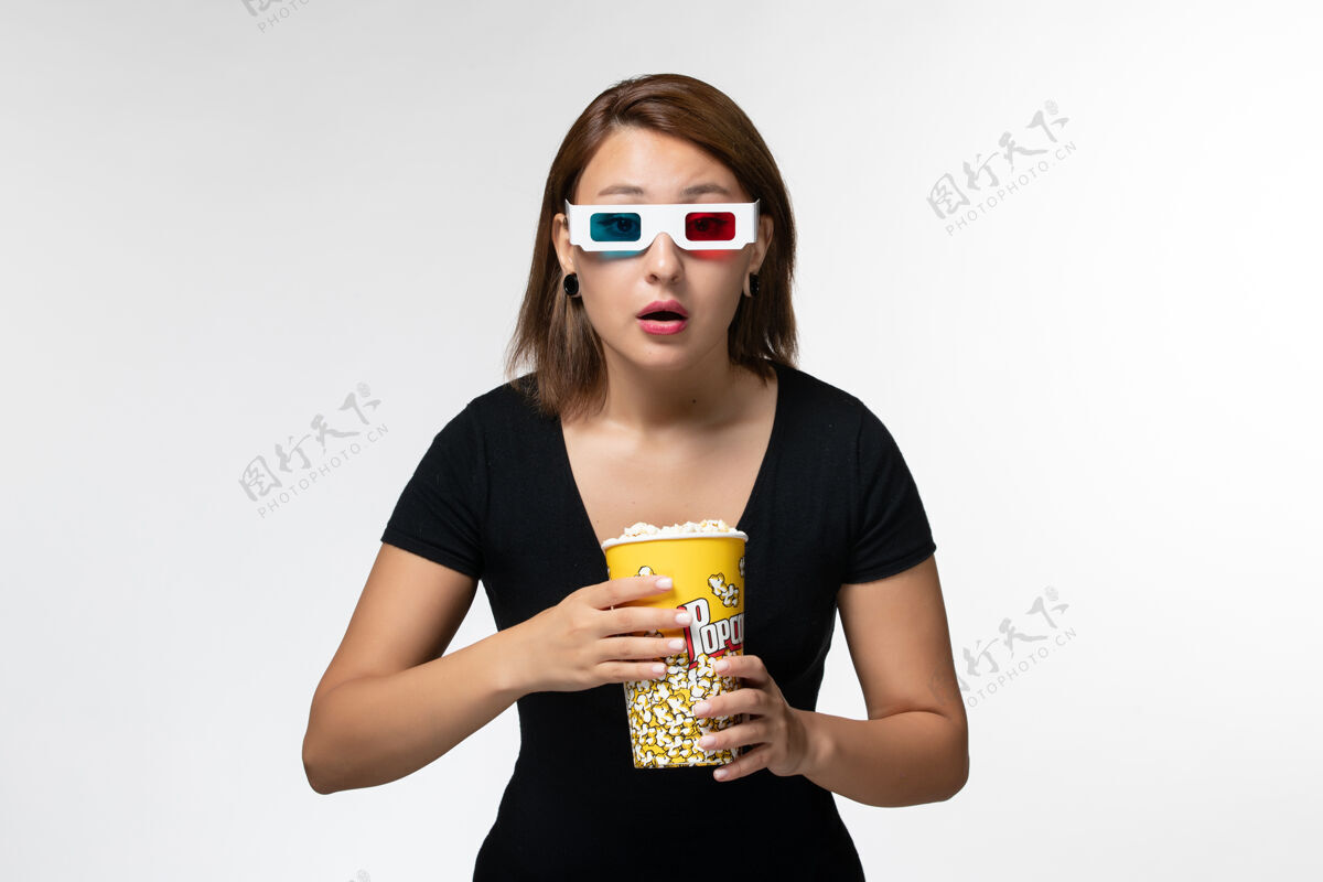 太阳镜正面图戴着d型太阳镜拿着爆米花的年轻女性在白色的表面上全神贯注地看电影举行电影电影