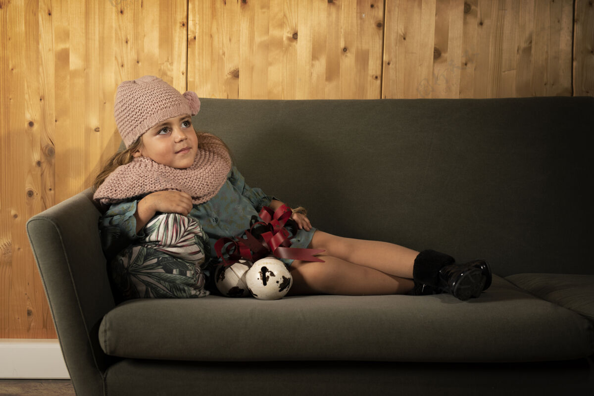 衣服穿着冬衣躺在沙发上 枕头靠在木墙上的小孩舒适谎言帽子