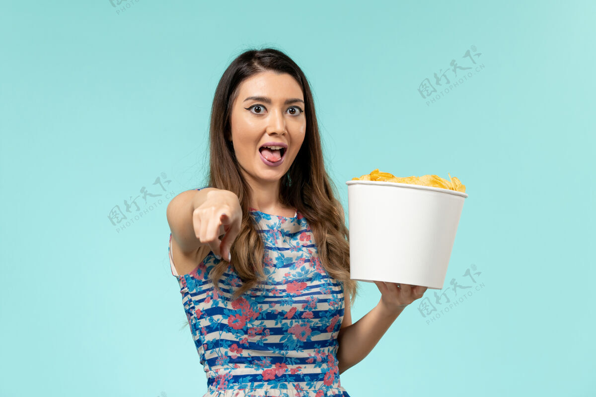 篮子正面图年轻的女性拿着篮子和筹码看电影 在蓝色的表面笑电影笑前面