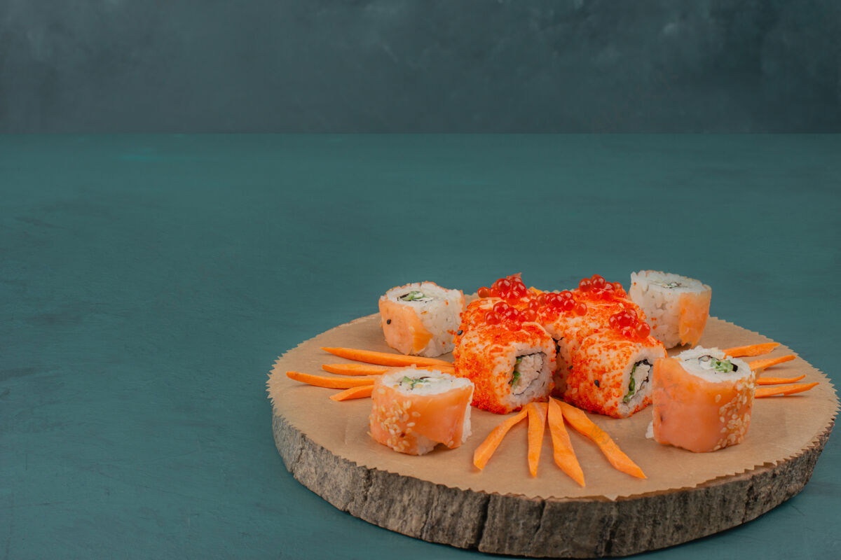鱼把寿司和胡萝卜片放在木板上搅拌加州费城切片