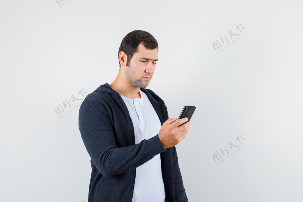 头发男青年穿着t恤衫 夹克衫 用手机 看上去很忙 前视图忙碌使用人