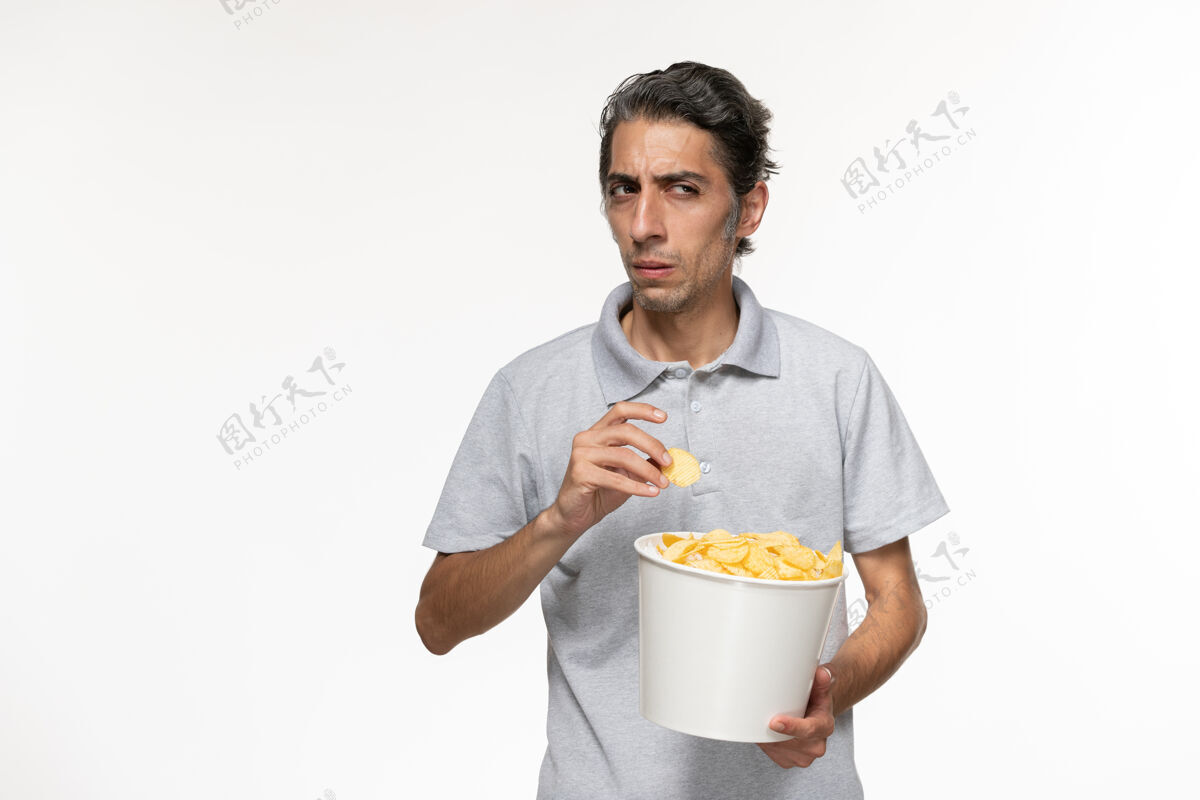年轻的男正面图年轻男性在白色表面吃薯片电影遥远男