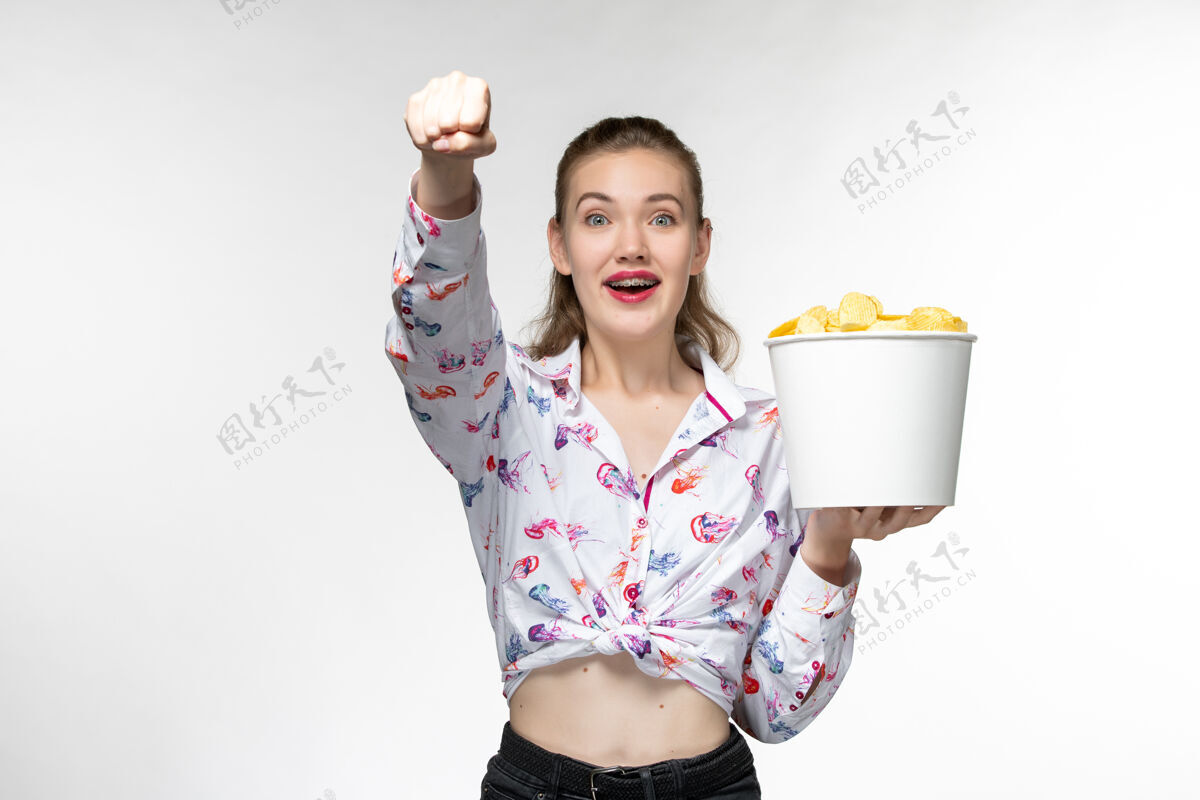 享受正面图：白色表面上放着薯片的年轻女性手提篮美丽篮子前面