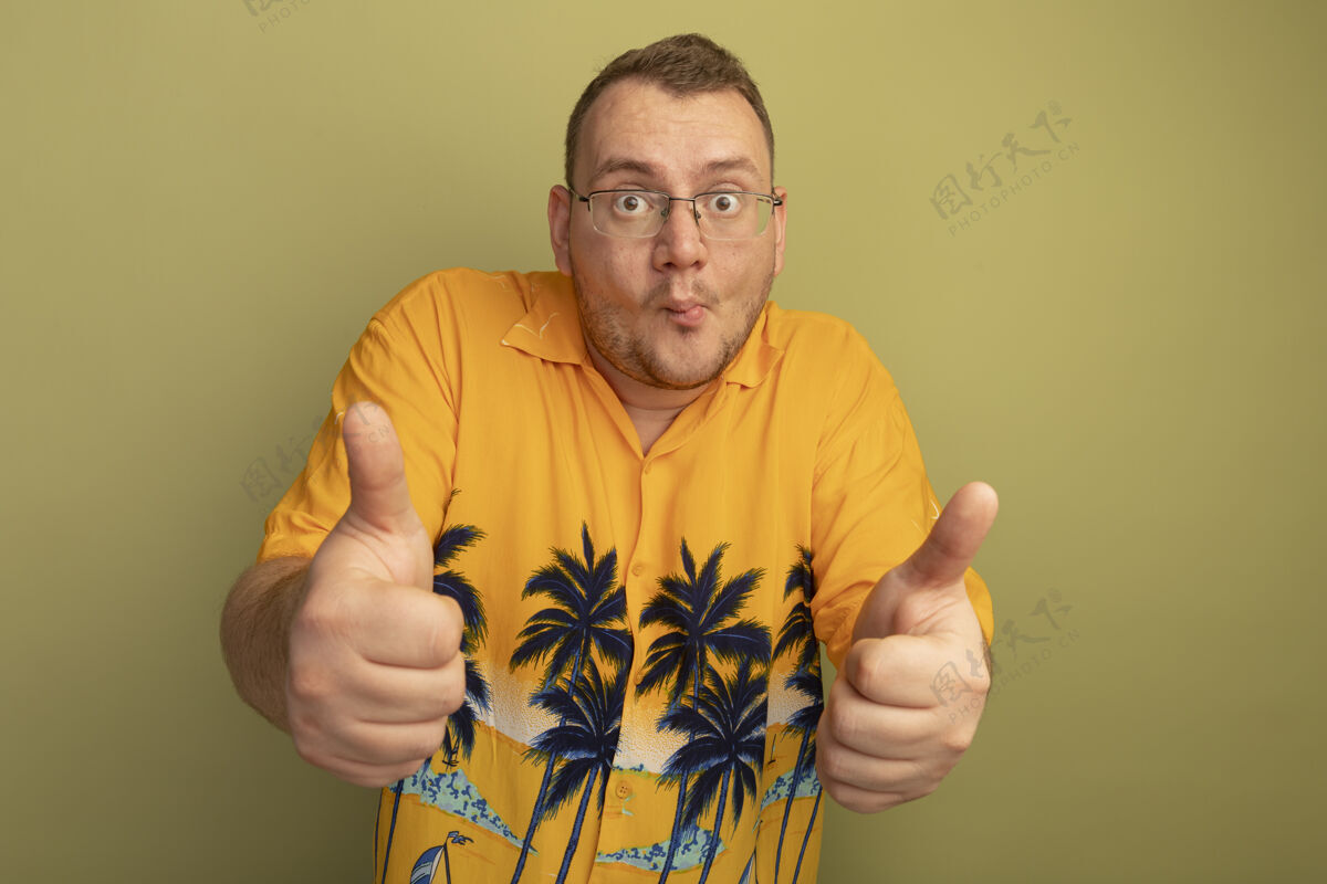 拇指一个戴着眼镜 穿着橙色衬衫的男人站在光墙上 困惑地竖起大拇指人站光