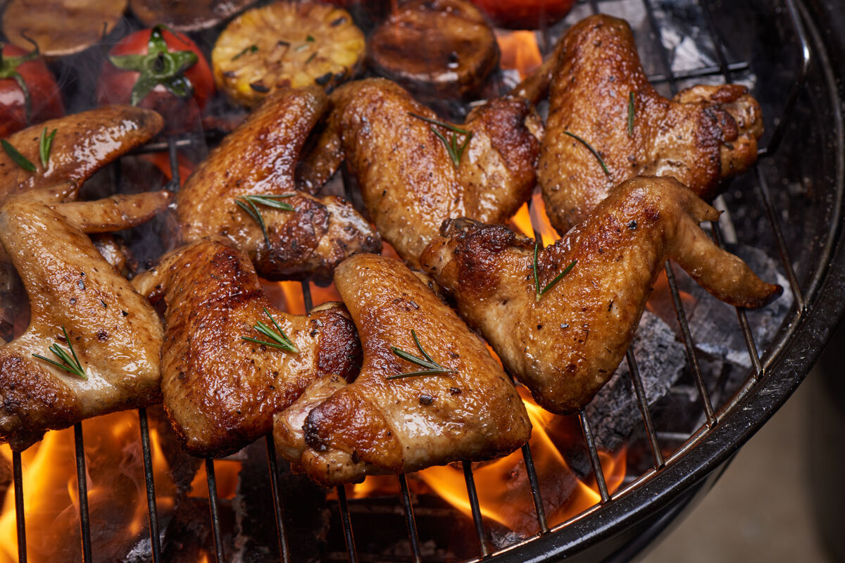 胡椒烤鸡翅在火焰烤架上 配烤蔬菜和胡椒籽 迷迭香 盐火野营金色