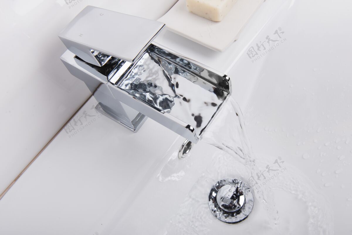 家庭现代和新的钢水龙头与陶瓷浴缸在浴室里倒水流钢